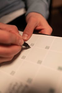 Close-up of a hand writing on a calendar after completing the IV Therapy Request form