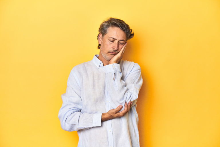 Fatigued middle-aged man against a yellow background, representing andropause