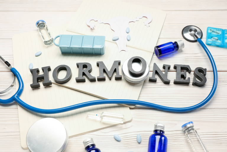 Word HORMONES with medications notebooks and stethoscope on white wooden background edited