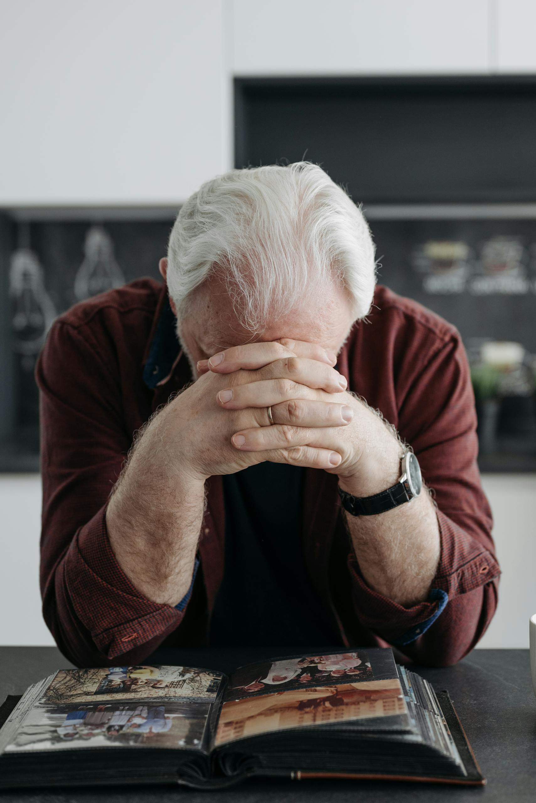 Therapeutic Plasma Exchange for Alzheimer's | Lifespan Health 1 Elderly man with white hair contemplating past memories through a photo album at home.