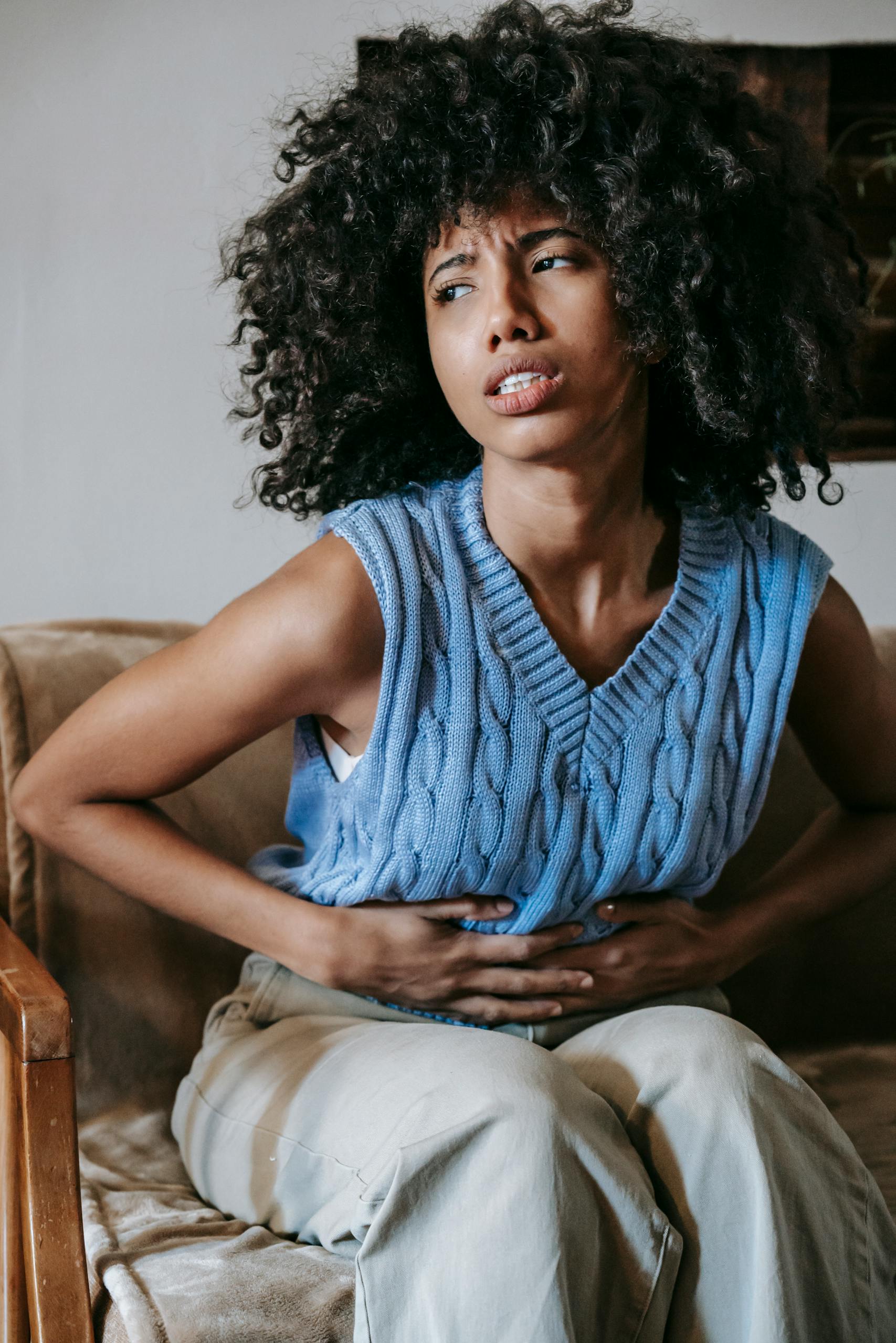 Gastrointestinal Disorders | Lifespan Health 2 Young African American female sitting on couch at home while having acute pain in stomach, representing Gastrointestinal Disorders